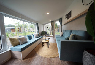 Lyst og hyggeligt opholdsområde i Panorama Cottage, et tiny house i Hoge Kempen, Belgien, med store vinduer.