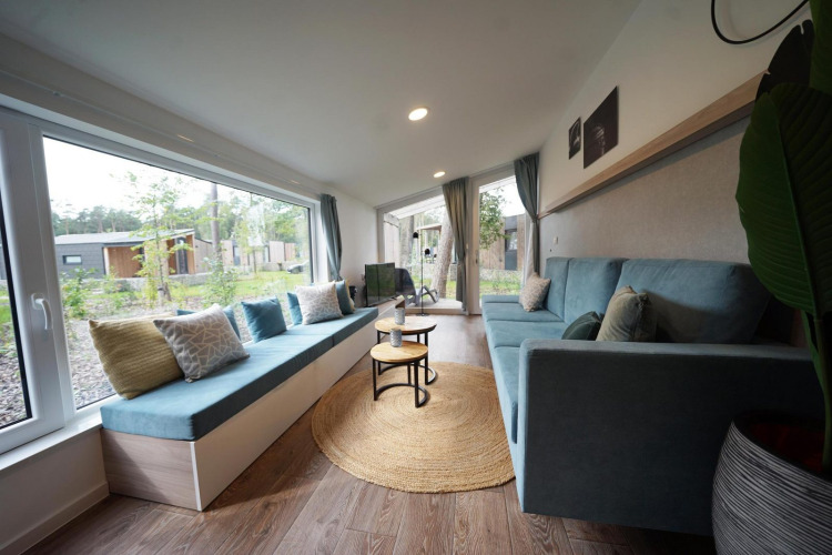 Acogedor salón luminoso en Panorama Cottage, una tiny house en Hoge Kempen, Bélgica, con grandes ventanales.