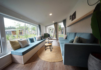 Zona giorno luminosa e accogliente nel Panorama Cottage, tiny house a Hoge Kempen, Belgio, con grandi finestre.