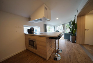Moderna cocina pequeña en Panorama Cottage, Hoge Kempen, Bélgica, con barra y suelo de madera.