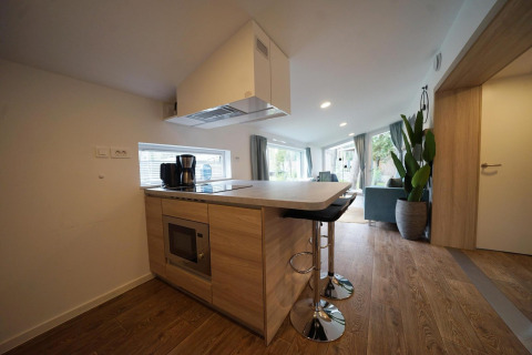 Modern small kitchen in Panorama Cottage, Hoge Kempen, Belgium, with breakfast bar and wooden flooring.