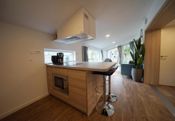 Moderne, lille køkken i Panorama Cottage, Hoge Kempen, Belgien, med træinteriør og barstole.