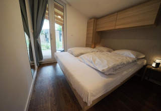 Moderne soveværelse i Panorama Cottage, Hoge Kempen, Belgien, med dobbeltseng og store vinduer.