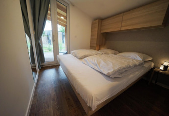 Moderne soveværelse i Panorama Cottage, Hoge Kempen, Belgien, med dobbeltseng og store vinduer.