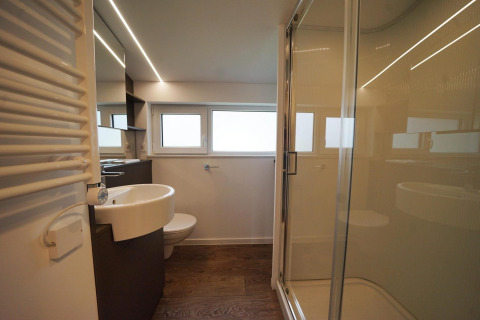 Baño moderno en Panorama Cottage, Hoge Kempen, Bélgica, con ducha de vidrio, lavabo y ventanales.