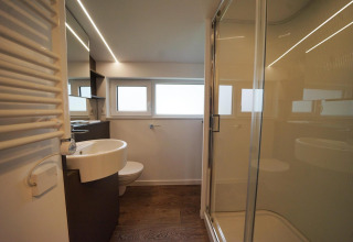 Baño moderno en Panorama Cottage, Hoge Kempen, Bélgica, con ducha de vidrio, lavabo y ventanales.