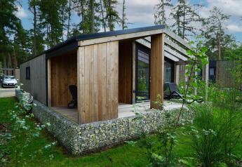 Panorama Cottage, et lille træhus i skoven ved Hoge Kempen i Belgien, omgivet af frodigt grønt.
