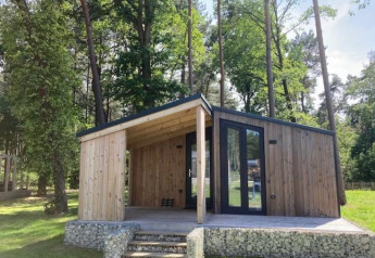 Panorama Cottage, una pequeña casa de madera en Hoge Kempen, Bélgica, rodeada de árboles y naturaleza.