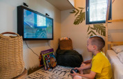 Dreng spiller videospil på tv på Kids Adventure cottage ved Hoge Kempen i Belgien, hyggeligt værelse.