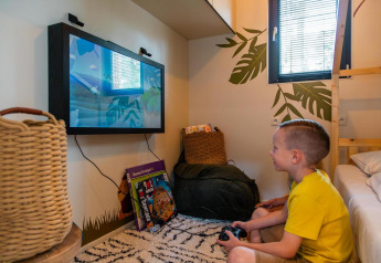 Garçon jouant à des jeux vidéo au Kids Adventure cottage à Hoge Kempen, Belgique, chambre douillette.