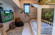 Camera per bambini al Kids Adventure cottage a Hoge Kempen, Belgio, con letto in legno e tema foresta.