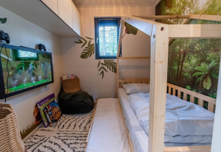 Chambre du Kids Adventure cottage à Hoge Kempen, Belgique, avec lit en bois et décor forêt tropicale.