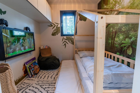 Chambre du Kids Adventure cottage à Hoge Kempen, Belgique, avec lit en bois et décor forêt tropicale.