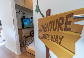 Stanza per bambini con cartello 'Adventure This Way' al Kids Adventure cottage, Hoge Kempen, Belgio.