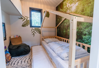 Dormitorio infantil en Kids Adventure cottage en Hoge Kempen, Bélgica, con cama de madera y mural de bosque.