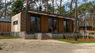 Moderne Modus Wellness lodge in Hoge Kempen, België, omringd door bomen en een natuurlijke sfeer.