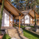 To Papendaal lodge telte i skoven, med træer omkring, sten- og græsstier foran indgangen.