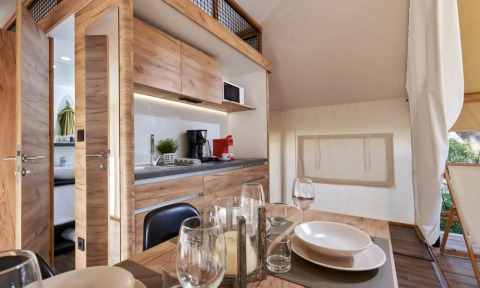 Interior de Papendaal Lodge en Hoge Kempen, Bélgica, con cocina de madera y mesa de comedor preparada.