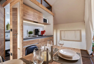 Interior de Papendaal Lodge en Hoge Kempen, Bélgica, con cocina de madera y mesa de comedor preparada.