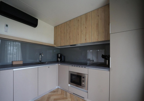 Moderne køkkenfaciliteter i Lieteberg cottage i Hoge Kempen, Belgien, med træskabe og grå vægge.