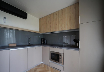 Moderne køkkenfaciliteter i Lieteberg cottage i Hoge Kempen, Belgien, med træskabe og grå vægge.