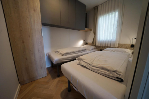Moderne lodge-værelse i Lieteberg-hytten, Hoge Kempen, Belgien, med to enkeltsenge og vindue.