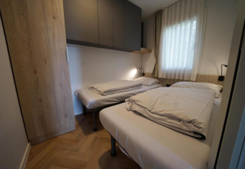 Moderne lodge-værelse i Lieteberg-hytten, Hoge Kempen, Belgien, med to enkeltsenge og vindue.
