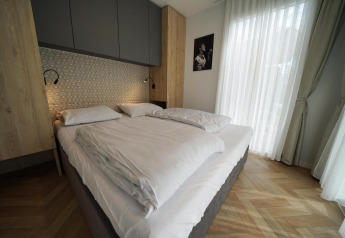 Modernes Schlafzimmer mit Doppelbett, Holzverkleidung und großen Fenstern in der Lieteberg Hütte, Belgien.