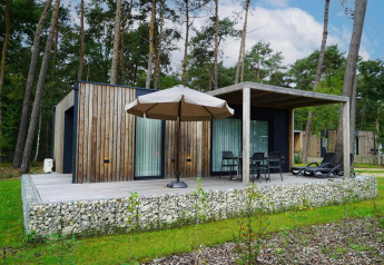 Trælodge ved Lieteberg cottage i Hoge Kempen, Belgien, omgivet af skov og med terrasse og møbler.
