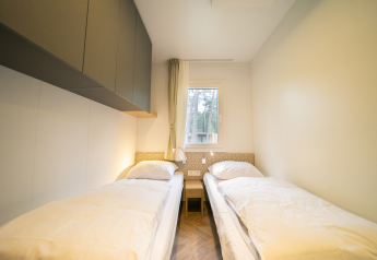 Dormitorio luminoso con dos camas individuales en la cabaña Lieteberg, Hoge Kempen, Bélgica, decorado simple.