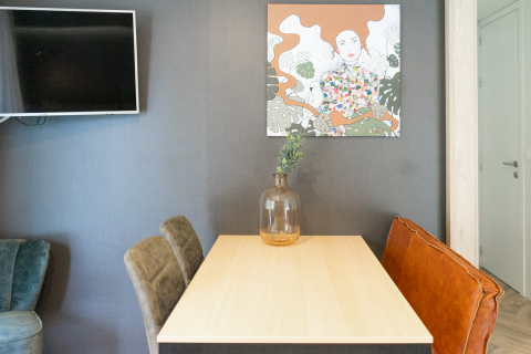 Espacio de comedor moderno en la cabaña Lieteberg, Hoge Kempen, Bélgica, con arte y un jarrón decorativo.