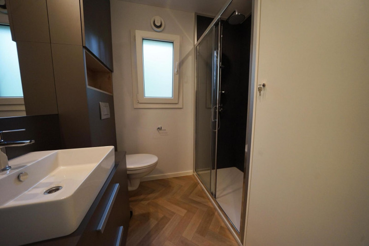 Baño moderno en la cabaña Lieteberg en Hoge Kempen, Bélgica, con ducha, lavabo y retrete a la vista.