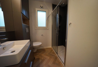 Baño moderno en la cabaña Lieteberg en Hoge Kempen, Bélgica, con ducha, lavabo y retrete a la vista.