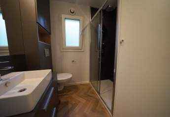 Baño moderno en la cabaña Lieteberg en Hoge Kempen, Bélgica, con ducha, lavabo y retrete a la vista.