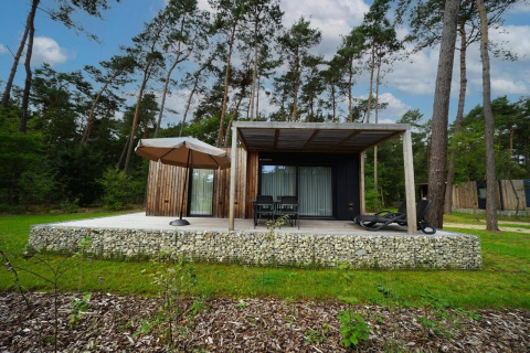 Modern Lieteberg cottage with patio and umbrella in the forest, Hoge Kempen National Park, Belgium.