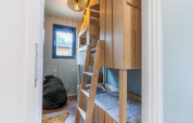 Chambre d’enfants avec lits superposés en bois, pouf et fenêtre au Kids cottage à Hoge Kempen, Belgique.