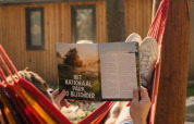 Iemand ligt in een hangmat en leest een tijdschrift bij de Papendaal Lodge safaritent in Hoge Kempen, België.