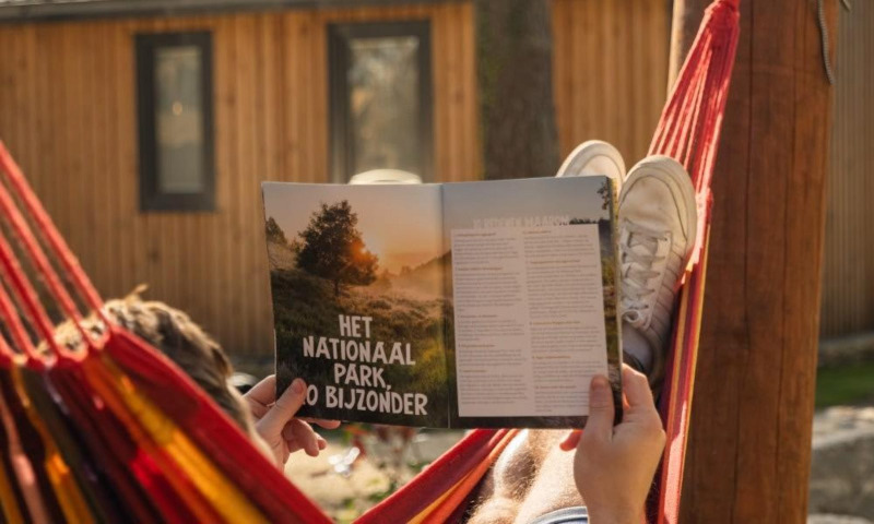 Una persona descansa en una hamaca leyendo una revista frente a la tienda Papendaal Lodge en Hoge Kempen, Bélgica.