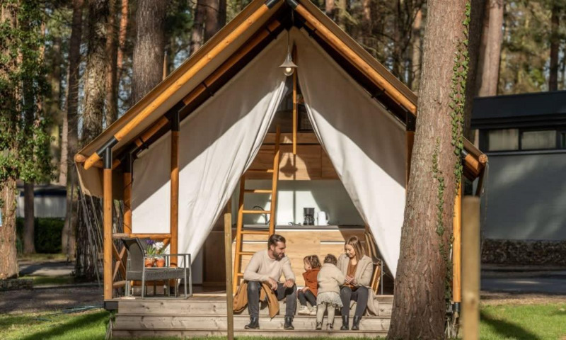 Eine Familie sitzt vor ihrem Papendaal Lodge Safarizelt im Wald und genießt die gemeinsame Zeit.