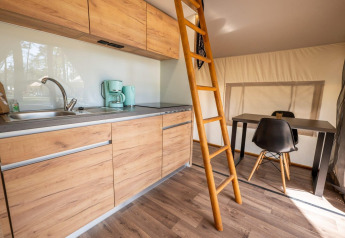 Cocina pequeña, mesa de comedor y escalera de madera en tienda safari Papendaal lodge en Hoge Kempen, Bélgica.