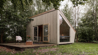 Modern tiny house with large windows in a forest, Luxe & Lazy Lodge at RØSTIG Dorst in the Netherlands.