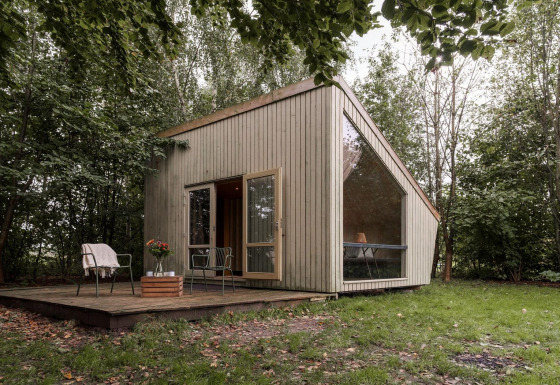 Modern tiny house with large windows in a forest, Luxe & Lazy Lodge at RØSTIG Dorst in the Netherlands.