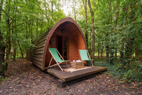 Großer Duo Pod aus Holz mit Terrasse und zwei grünen Liegestühlen im Wald bei RØSTIG Dorst, Niederlande.