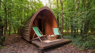 Pod in legno Duo Pod Large con veranda e due sedie a sdraio verdi nella foresta di RØSTIG Dorst, Paesi Bassi.