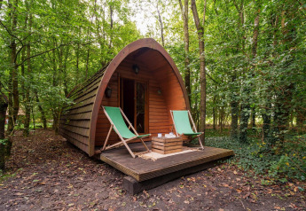 Træpod Duo Pod Large med terrasse og to grønne liggestole i skovområdet ved RØSTIG Dorst, Holland.