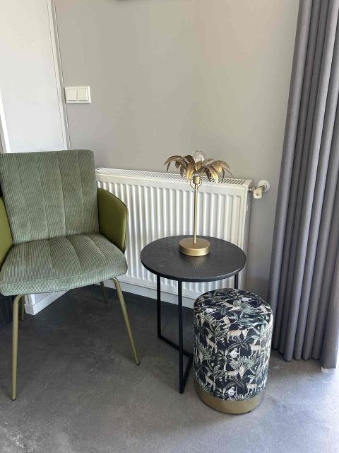 Stijlvol salonhoekje met groene stoel, rond zwart tafeltje en motiefpouf bij North Sea DeLuxe, Vakantiepark de Zeeuwse Parel.