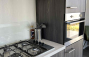 Cocina moderna en la cabaña North Sea DeLuxe de Vakantiepark de Zeeuwse Parel, Países Bajos, con estufa.
