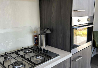 Modern kitchen in North Sea DeLuxe lodge at Vakantiepark de Zeeuwse Parel, Netherlands, with stove and oven.
