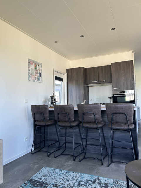 Moderne keuken met vier hoge stoelen in North Sea DeLuxe van Vakantiepark de Zeeuwse Parel, Nederland.