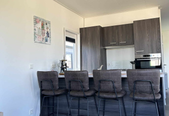 Moderne keuken en eetgedeelte met vier barkrukken bij North Sea DeLuxe, Vakantiepark de Zeeuwse Parel, Nederland.